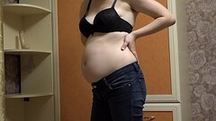 Pregnant milf takes off her tight jeans, puts on a sexy outfit, and masturbates her hairy pussy with Thumb